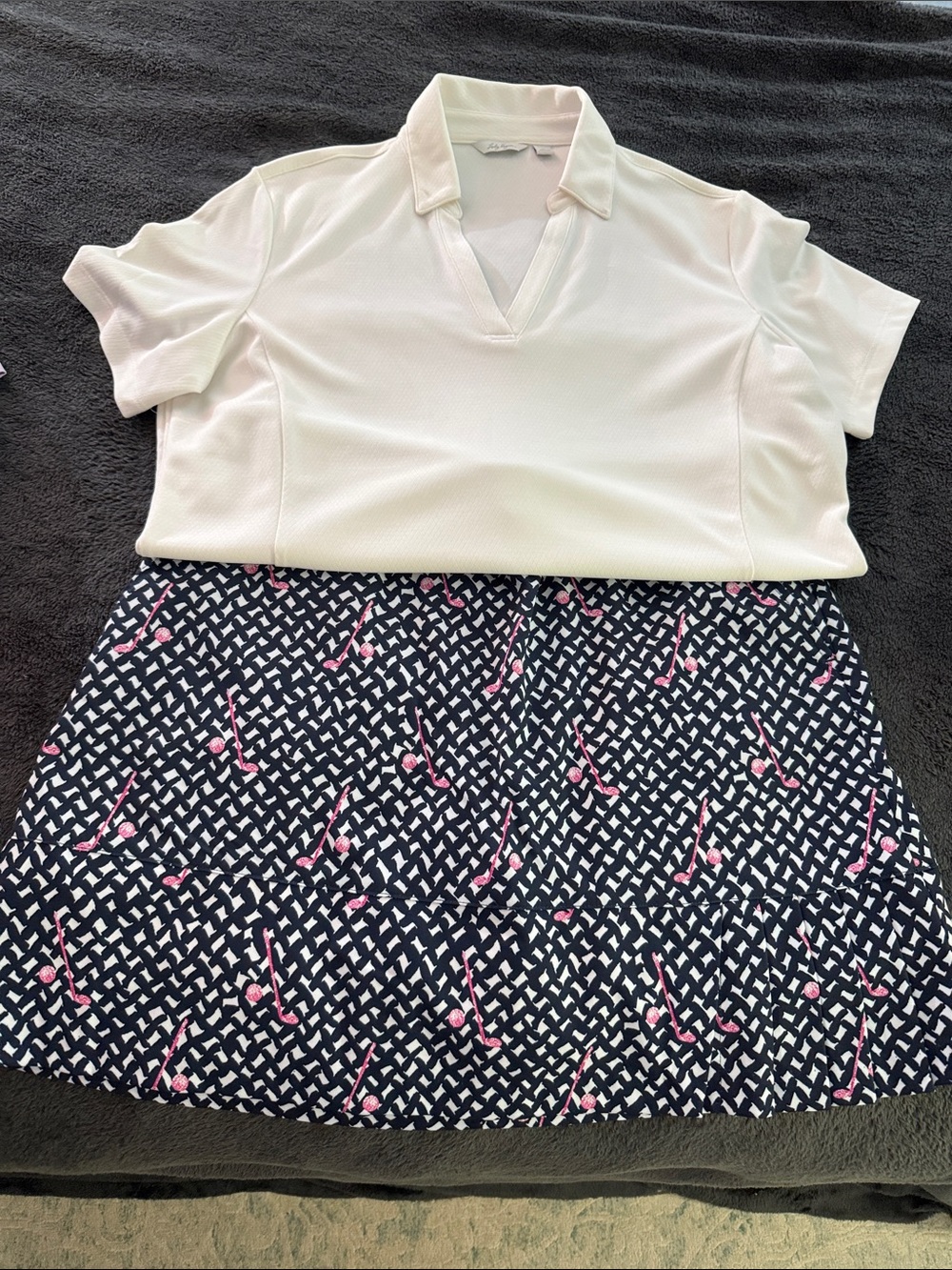 Lady Hagen Navy Skort with Pink golf clubs and white shirt.
